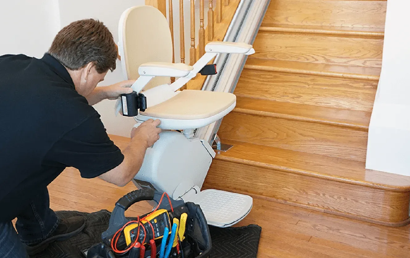Stairlift repair technician diagnosing electrical components on a chair lift